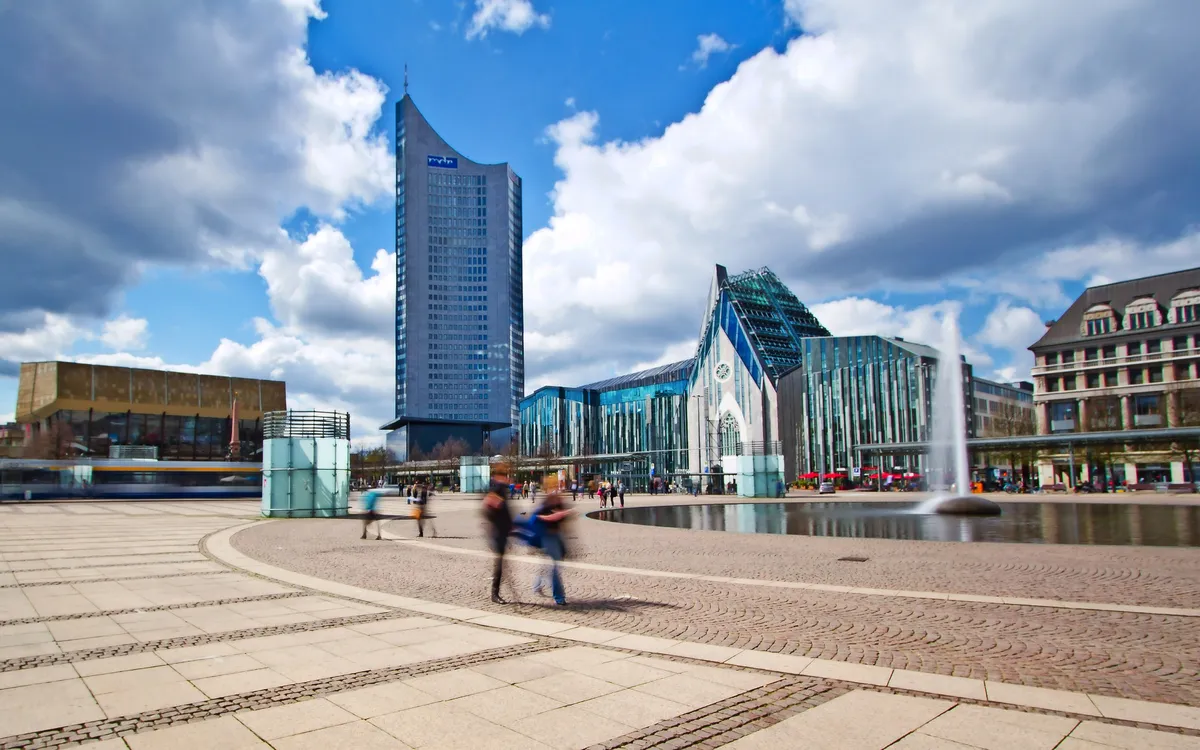 Straßenansicht in Leipzig mit zeitgenössischen Gebäuden und blauem Himmel.