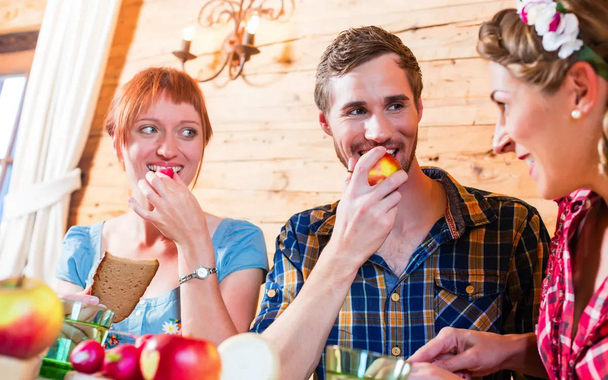 Drei Personen essen gemeinsam in einer Holzhütte.