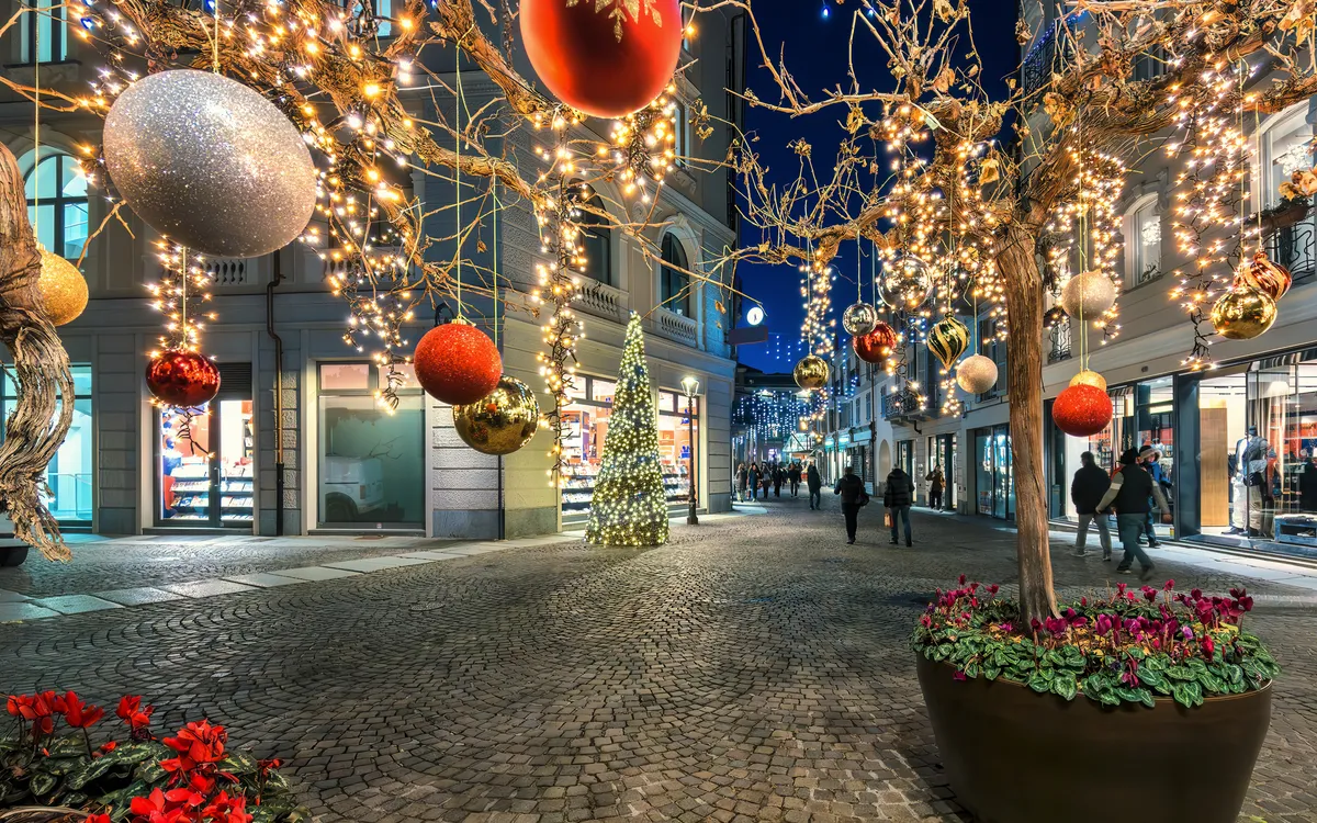 Beleuchtete Straße mit Weihnachtsdekorationen und Weihnachtsbaum in der Nacht.