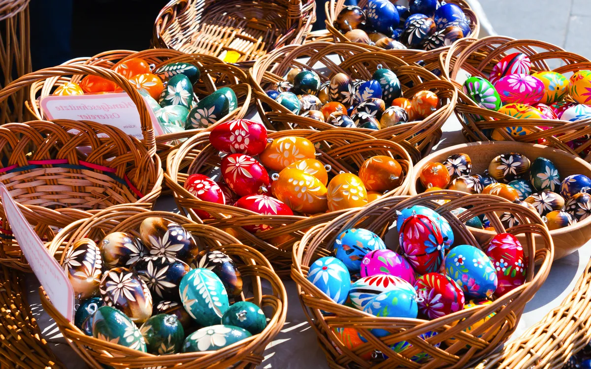 Bemalte Ostereier in bunten Farben in Weidenkörben auf einem Ostermarkt.