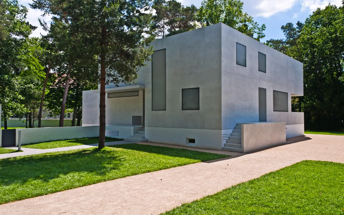 Modernes, kubisches Haus in einem grünen Parkumfeld.