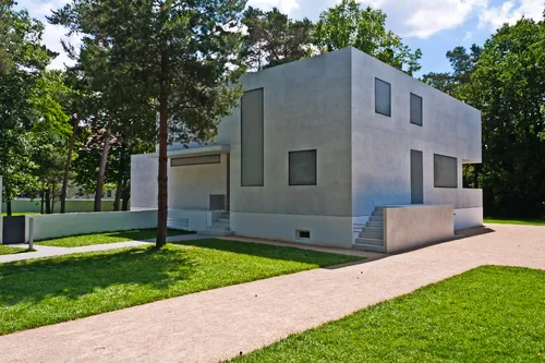 Modernes, kubisches Haus in einem grünen Parkumfeld.