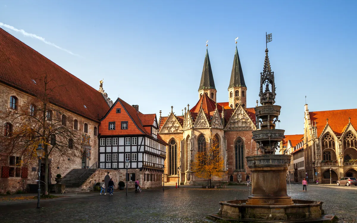 Historischer Platz mit Kirche und Fachwerkhäusern bei blauem Himmel.