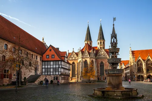 Historischer Platz mit Kirche und Fachwerkhäusern bei blauem Himmel.