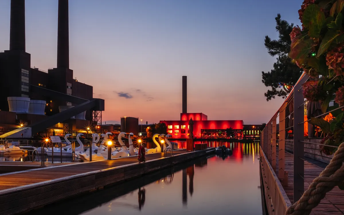 Abendstimmung bei einem Festival mit beleuchteten Gebäuden am Wasser.