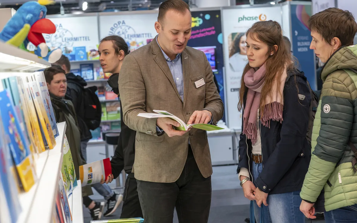 Person erklärt einer Gruppe von Menschen ein Buch auf der Leipziger Messe.