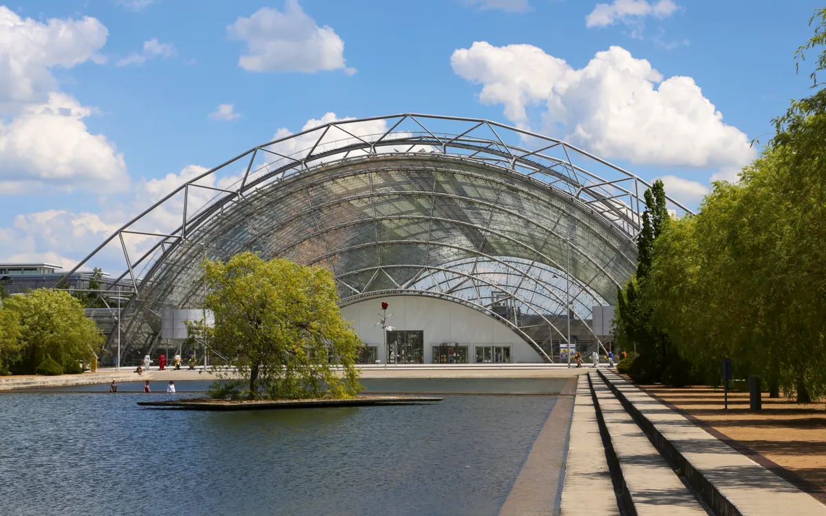 Messegebäude mit Glaskuppel und Wasserbecken in Leipzig bei klarem Himmel.