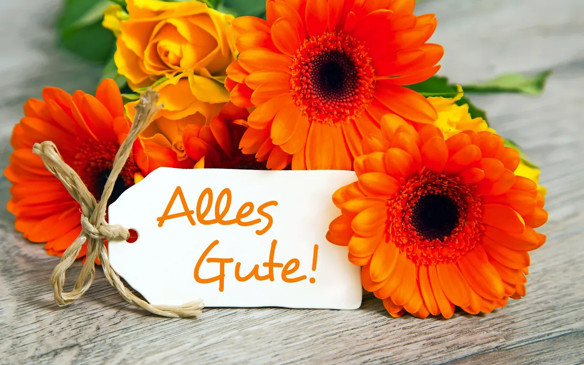 Blumenstrauß mit Rosen und Gerbera, Schild mit Aufschrift "Alles Gute".
