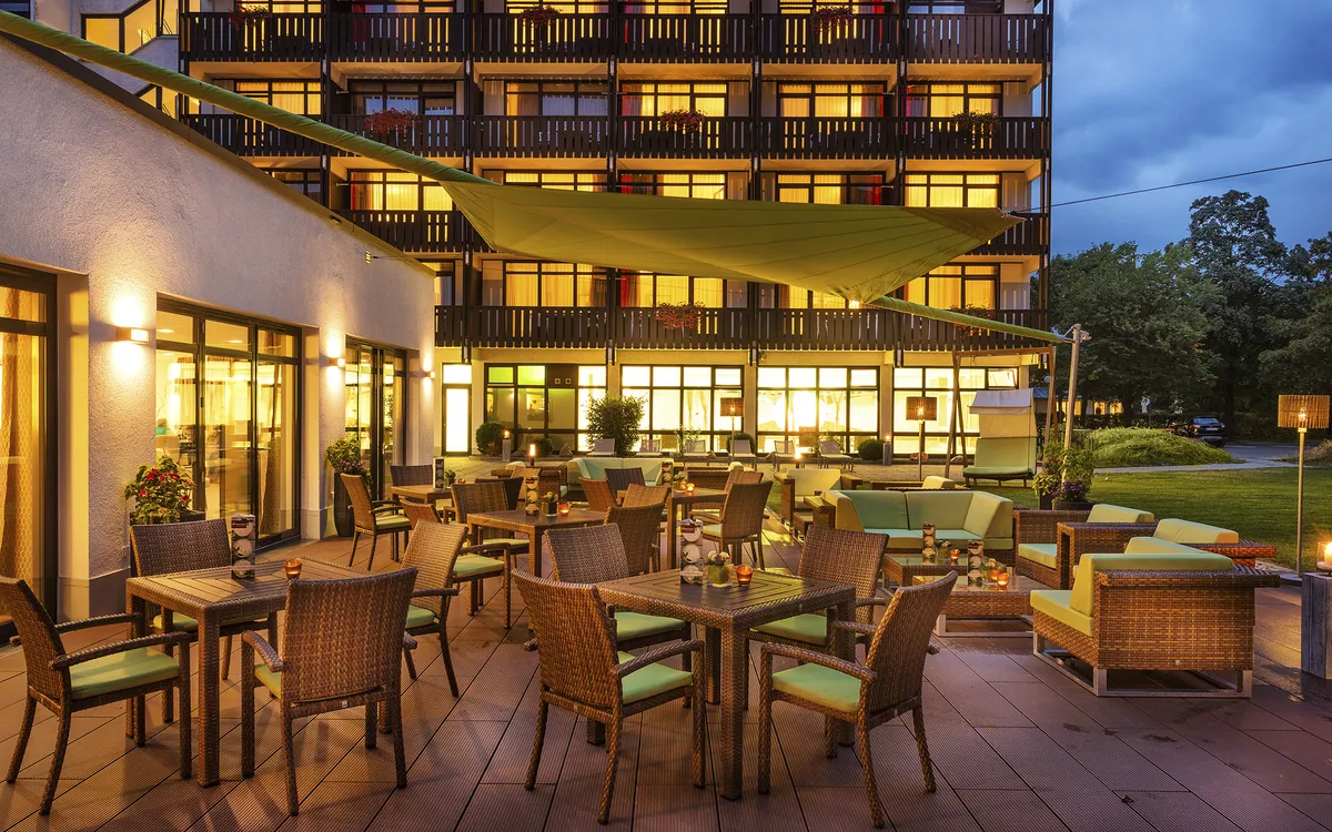 Terrasse eines Hotels mit Tischen und Stühlen in Bad Füssing am Abend