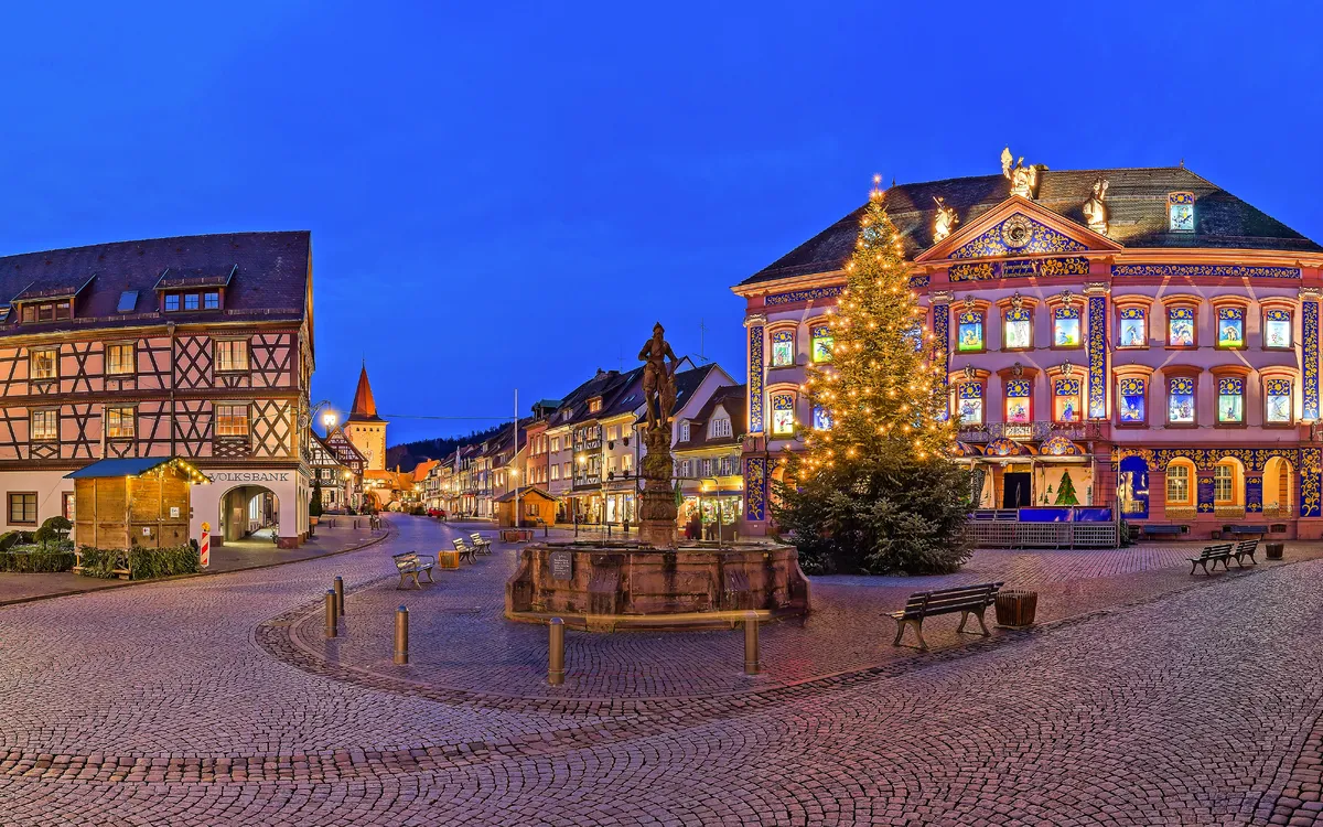 Festlich beleuchteter Platz mit Fachwerkhäusern und geschmücktem Weihnachtsbaum.