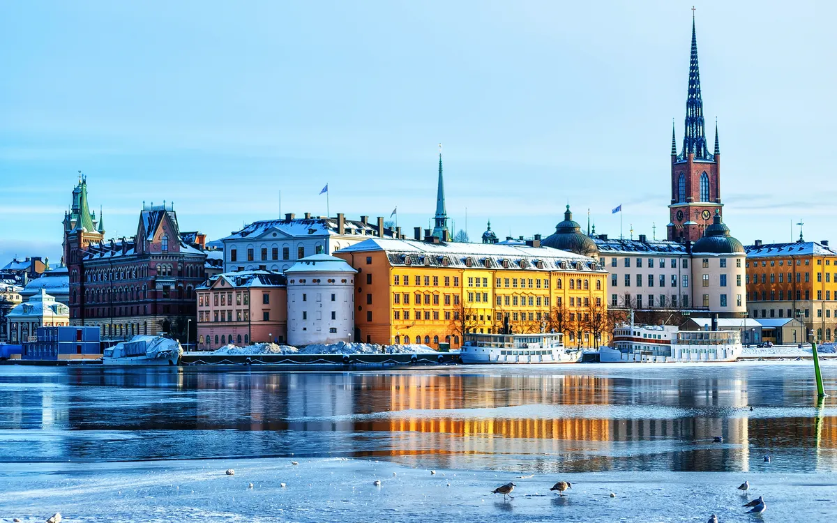 Bunte Gebäude am Wasser in einer Stadt mit Kirchturm im Winter.