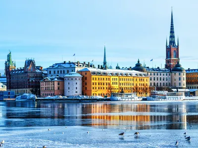 Bunte Gebäude am Wasser in einer Stadt mit Kirchturm im Winter.