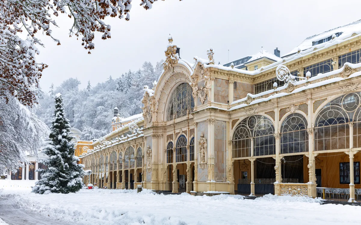 Verschneite Hauptkolonnade mit Weihnachtsbaum im Kurort Mariánské Lázně in Böhmen, Tschechien.