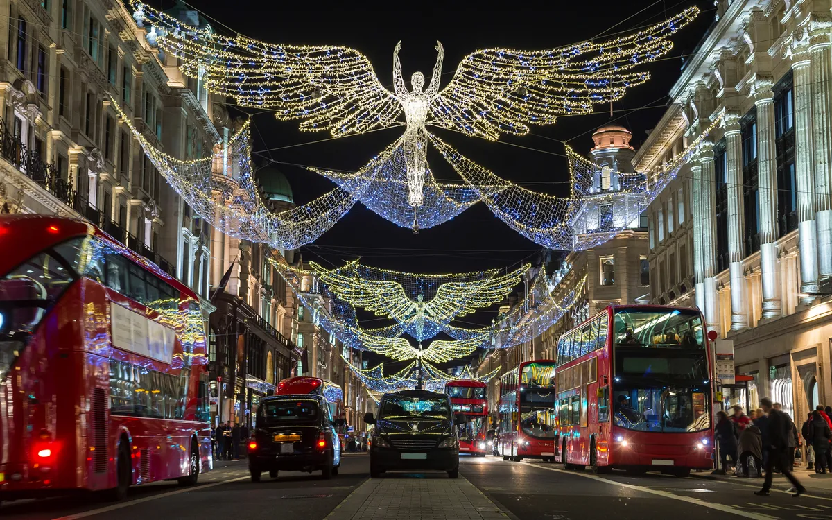 Straßenszene mit Weihnachtsbeleuchtung und roten Doppeldeckerbussen bei Nacht