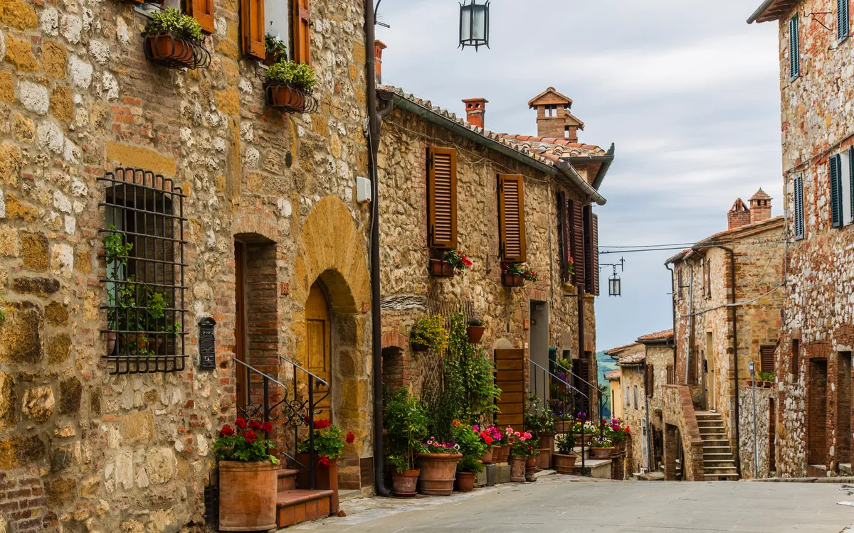 Typische mittelalterliche Gasse in der Toskana mit Blumenkästen an den Steinmauern eines Dorfes.