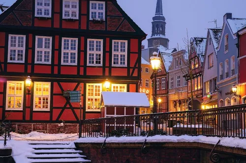 Verschneite Altstadt mit Fachwerkhäusern und Kirchturm im Hintergrund.