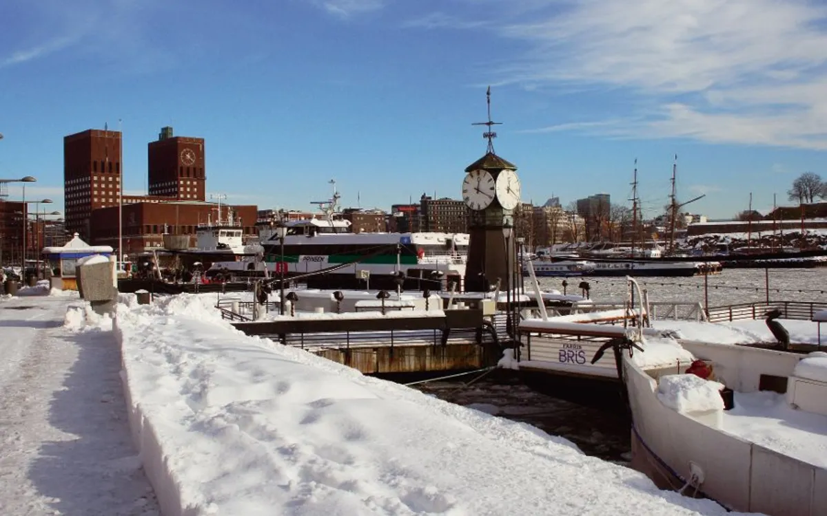 Winterliches Hafenviertel Aker Brygge in Oslo mit Blick auf das Rathaus.