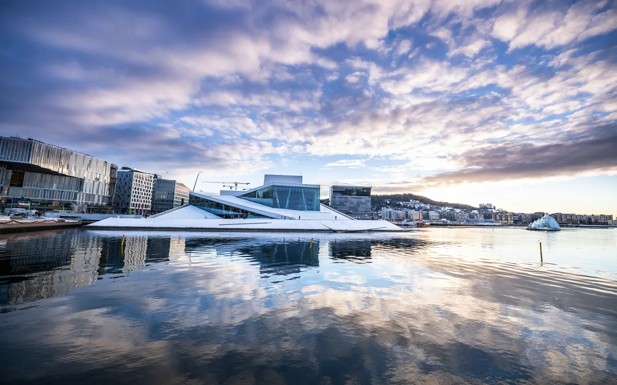 Oslos Opernhaus im Winter mit Schnee und reflektierendem Wasser im Vordergrund