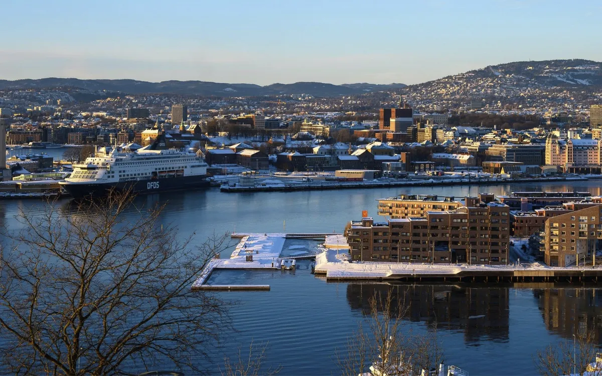 Hafenstadt mit verschneiten Gebäuden und Fährschiff bei klarem Himmel.