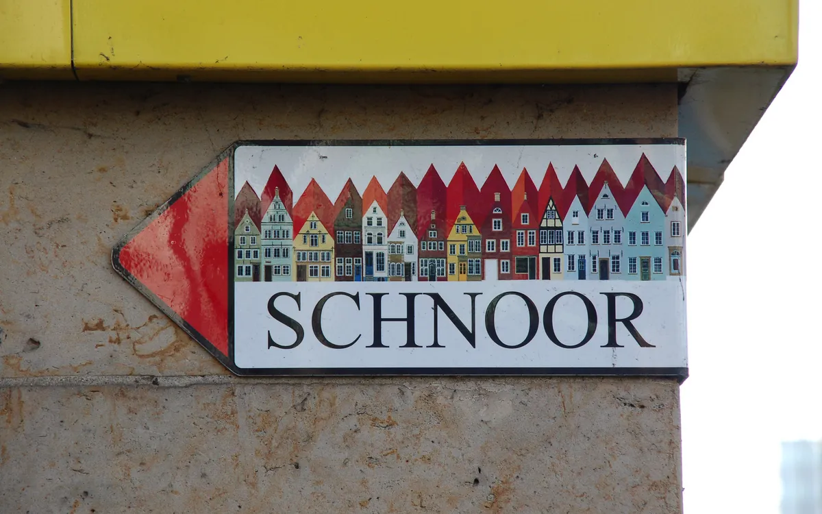 Straßenschild mit bunten Häusern und dem Wort Schnoor.
