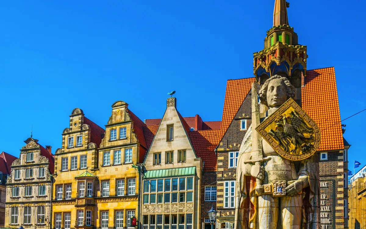 Rathausplatz in Bremen mit der Statue des Roland und bunten Fassaden im Hintergrund.