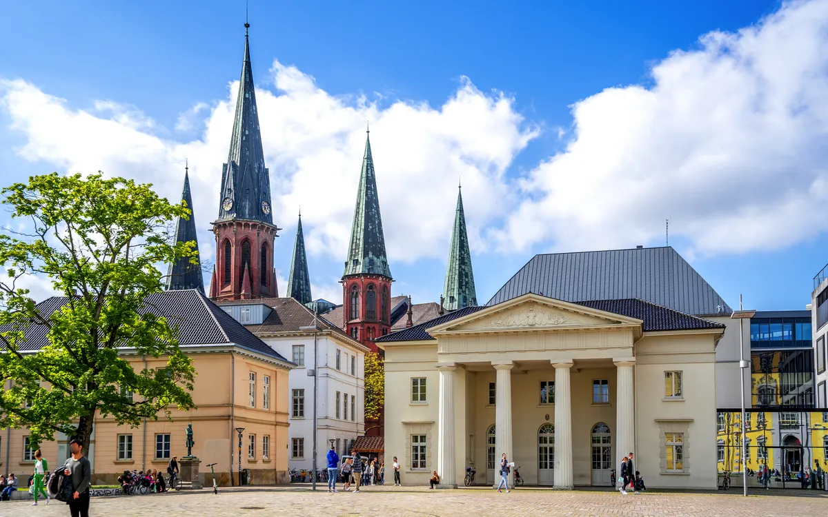 Historischer Platz mit Gebäuden und Kirchtürmen bei sonnigem Wetter.