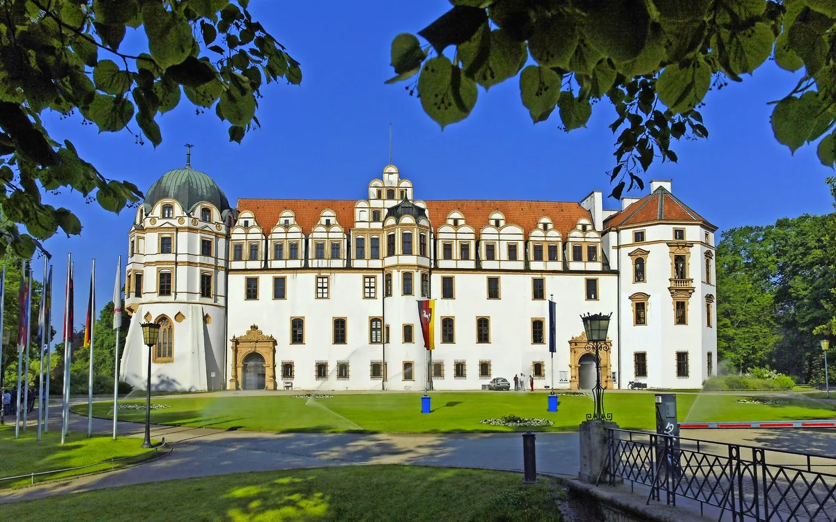 Schloss Celle in Deutschland mit grüner Umgebung und blauem Himmel.