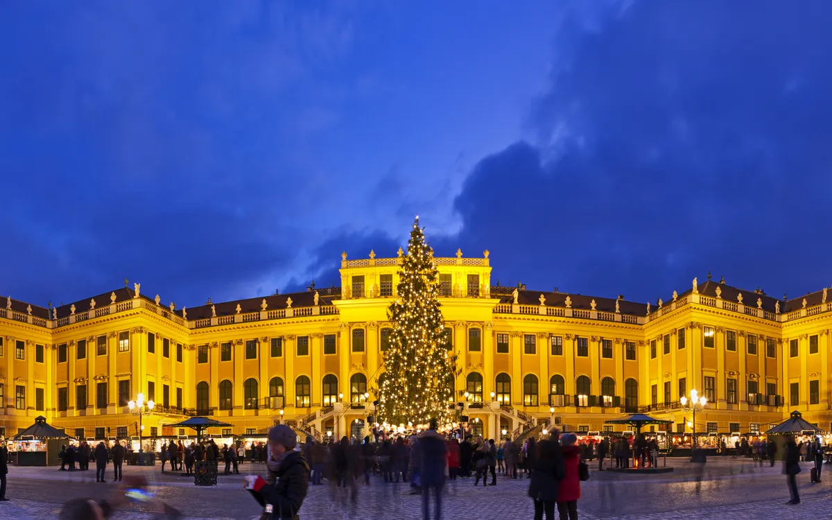 Weihnachtsmarkt am Schloss Schönbrunn bei Dämmerung mit Weihnachtsbaum.