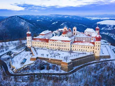 Luftaufnahme eines schneebedeckten Klosters auf einem Hügel im Winter.