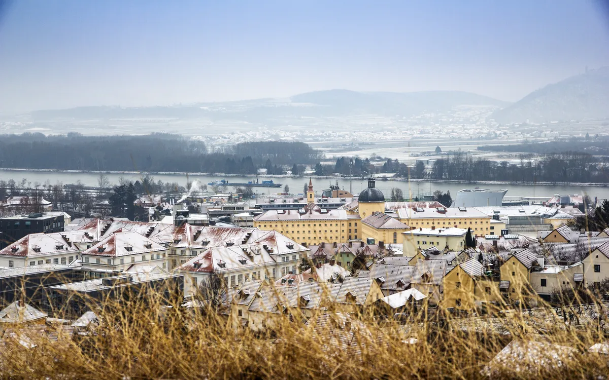 Verschneite Stadtlandschaft mit Fluss im Hintergrund