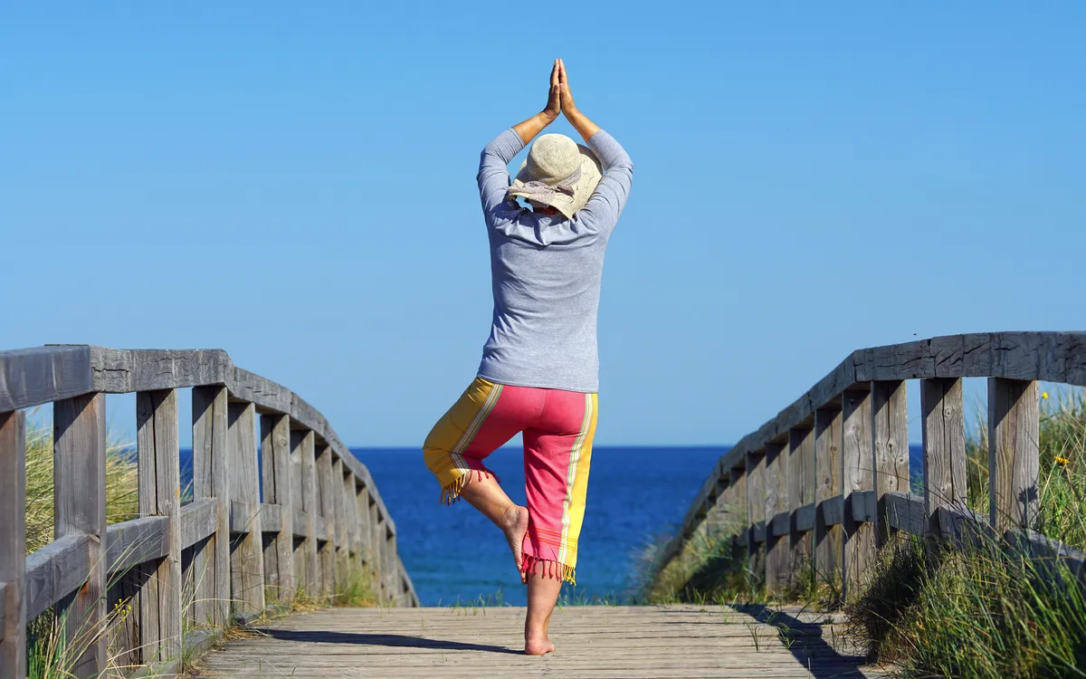 Frau in Yoga Pose am Strandübergang