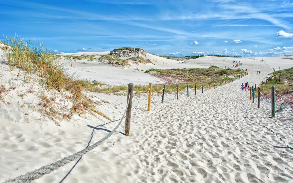 Touristen wandern durch die Sanddünen des Słowiński-Nationalparks