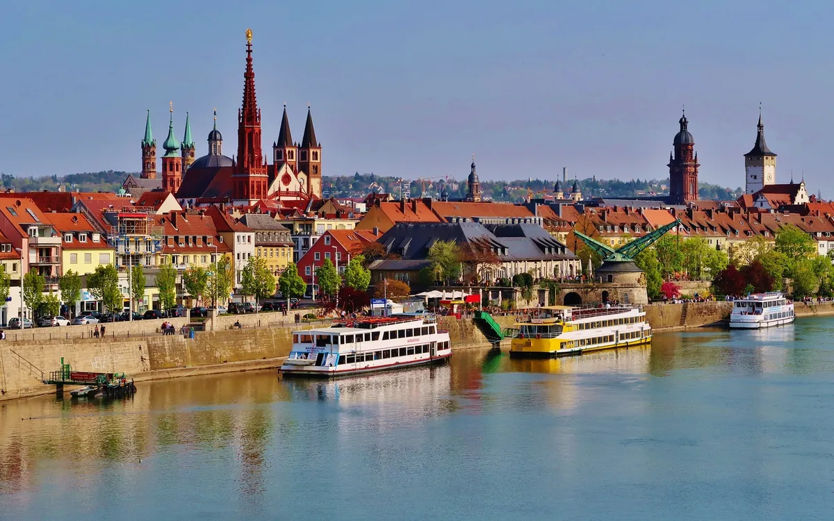 Stadtansicht von Würzburg mit Main und Schiffen im Vordergrund.