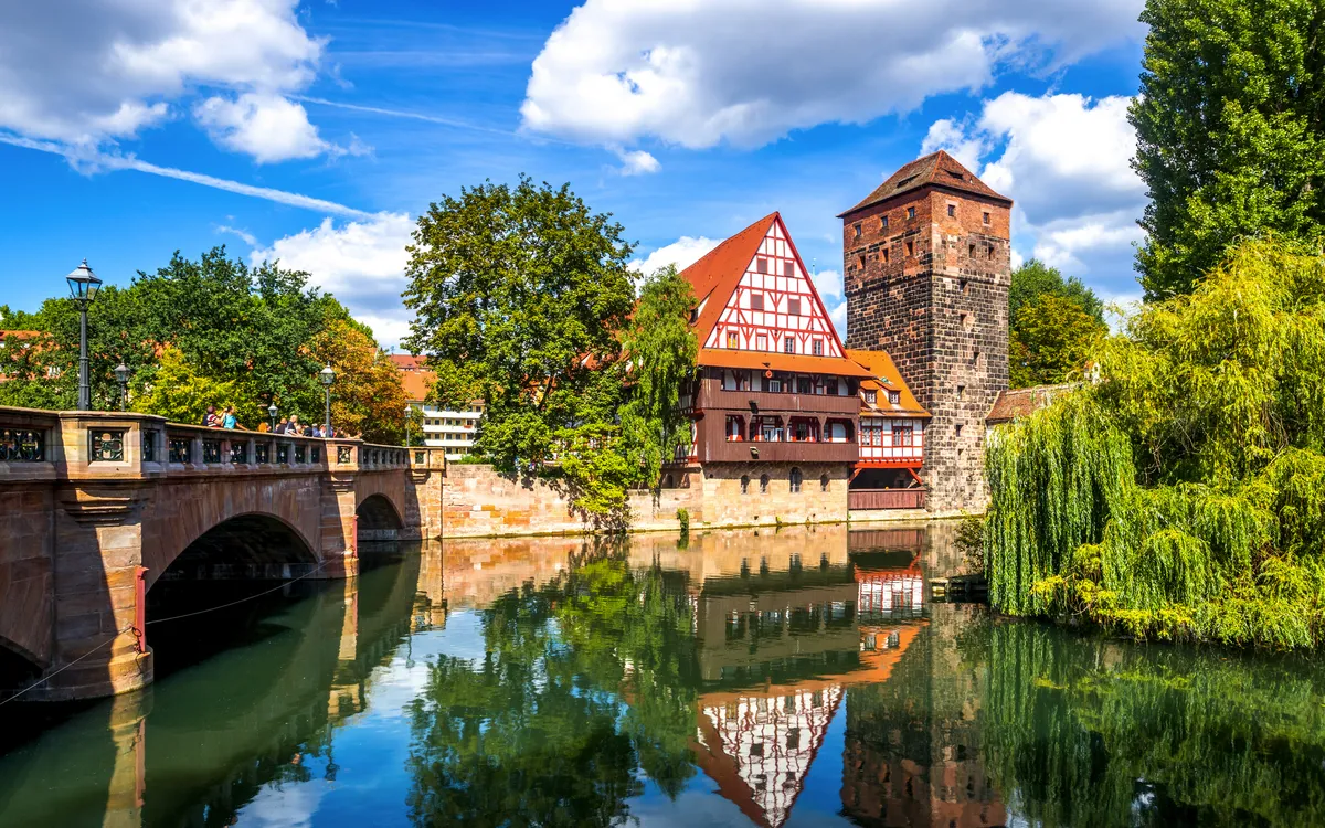 Fachwerkhaus und Turm am Fluss in Nürnberg unter blauem Himmel