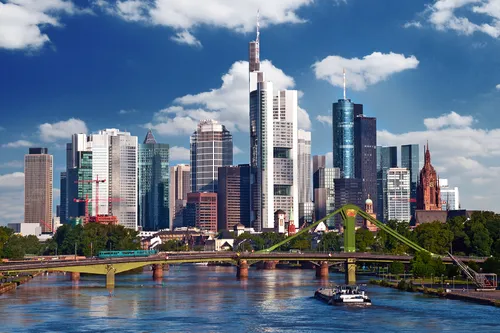 Skyline von Frankfurt am Main mit Wolkenkratzern und Fluss im Vordergrund.