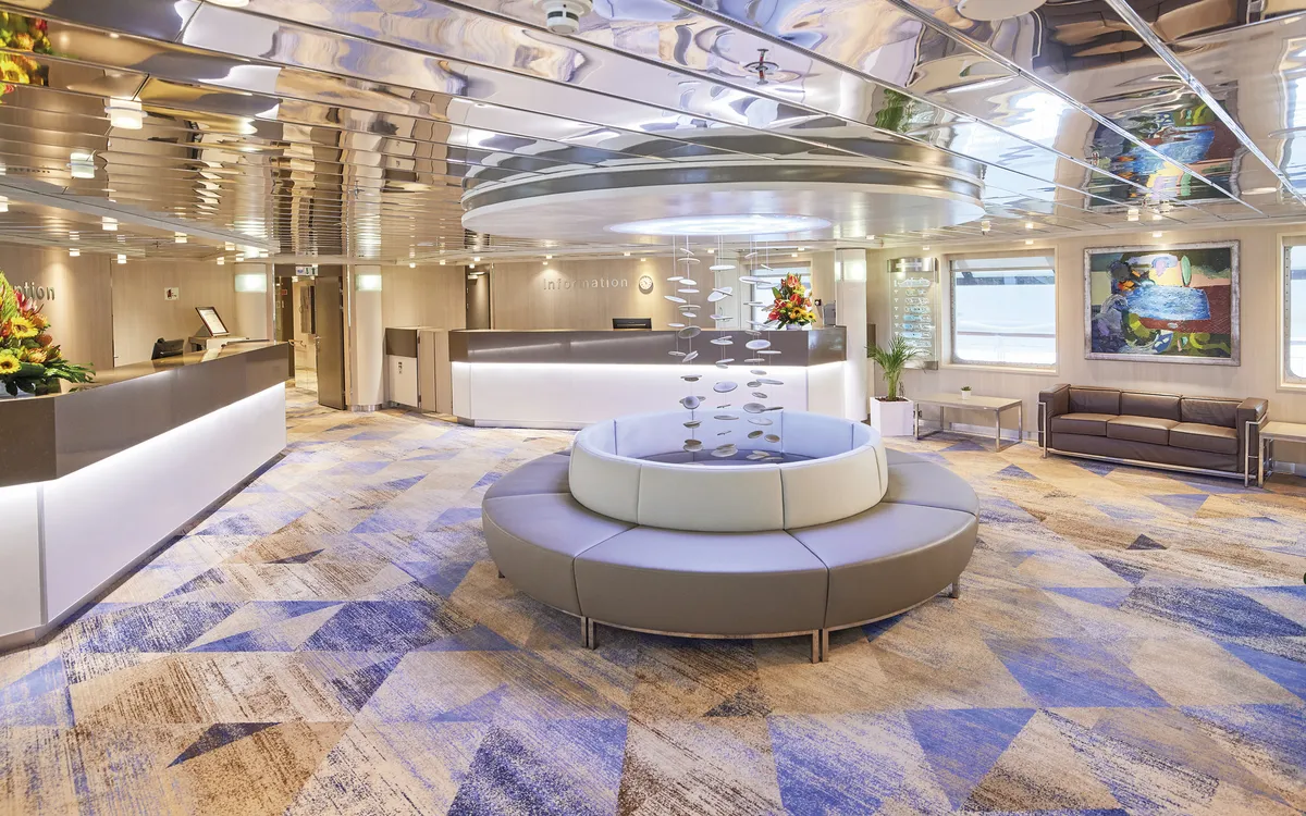 Moderne Lobby der MS Hamburg mit Sitzbereich und dekorativer Deckeninstallation.