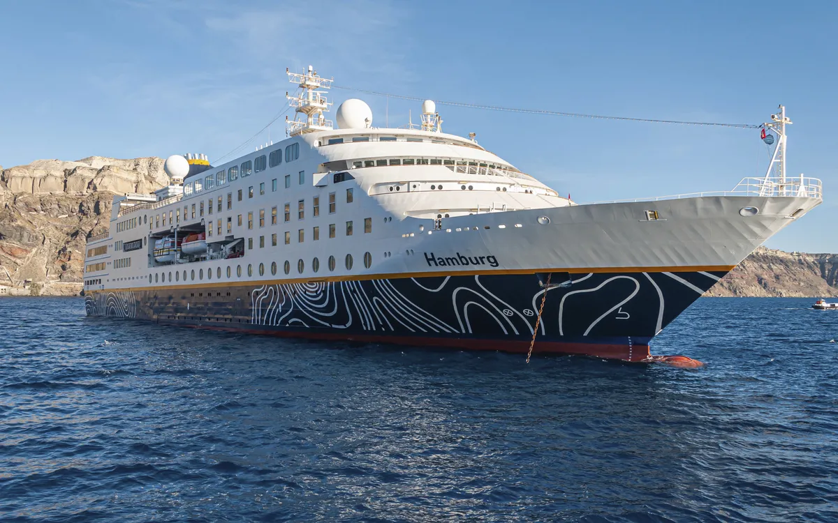 Kreuzfahrtschiff MS Hamburg vor Küstenlandschaft bei Santorin.