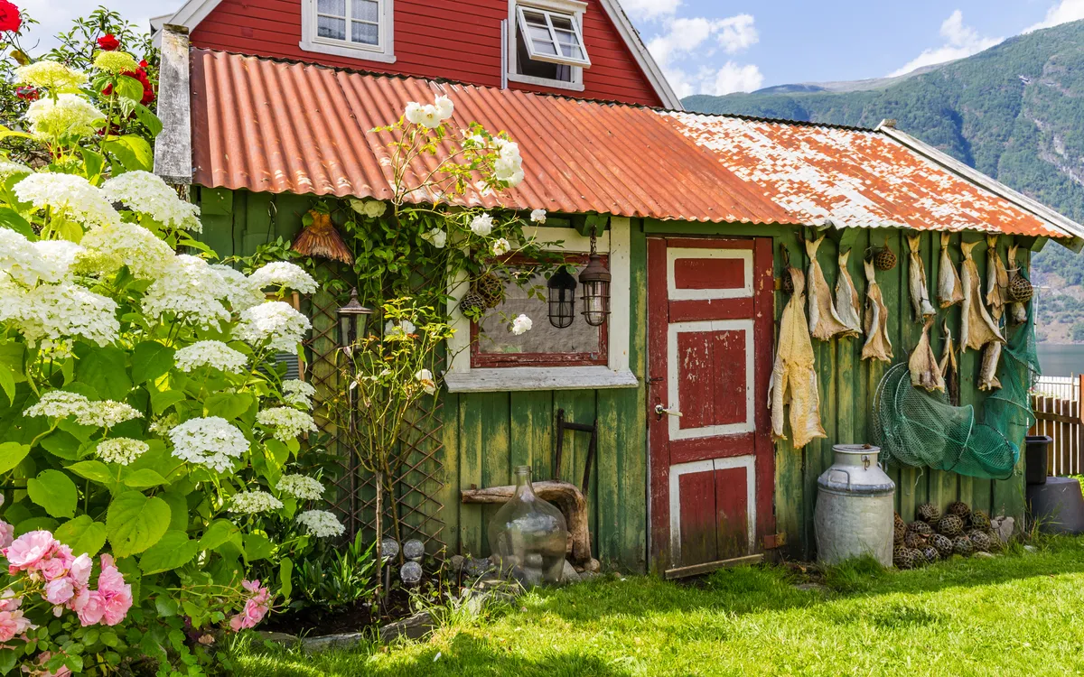 Rotes Haus am Aurlandsfjordufer, umgeben von Blumen in Norwegen.