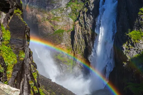 Wasserfall Vøringsfossen in Norwegen mit einem Regenbogen im Vordergrund.