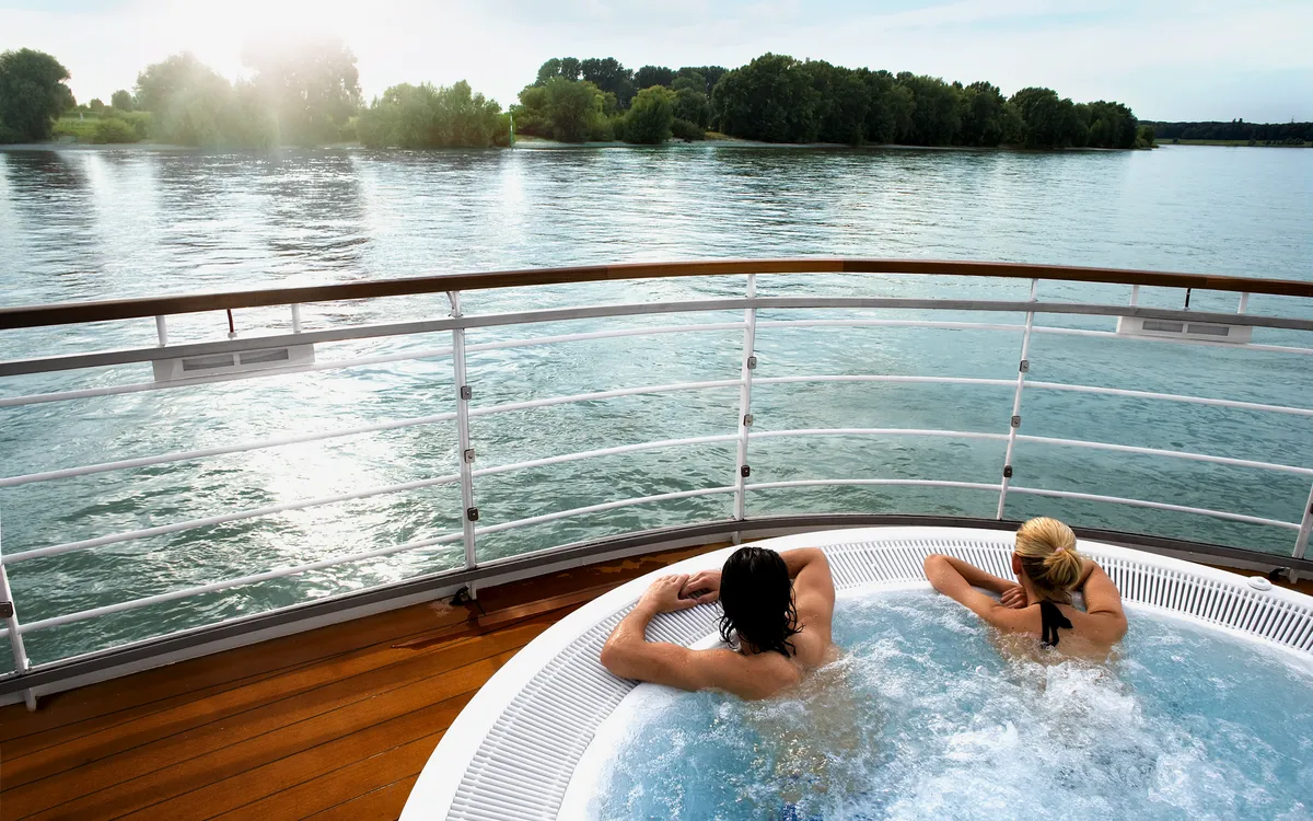 Personen im Whirlpool auf einem Flussschiff mit Blick auf den Rhein.