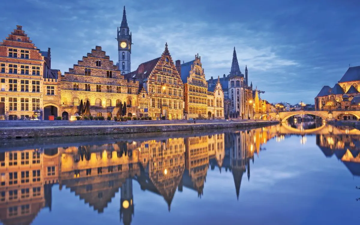 Gent bei blauer Stunde mit Lichtern an den Flussufern.