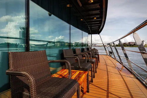 Rattansessel auf sonnigem Deck mit Aussicht auf das Wasser.