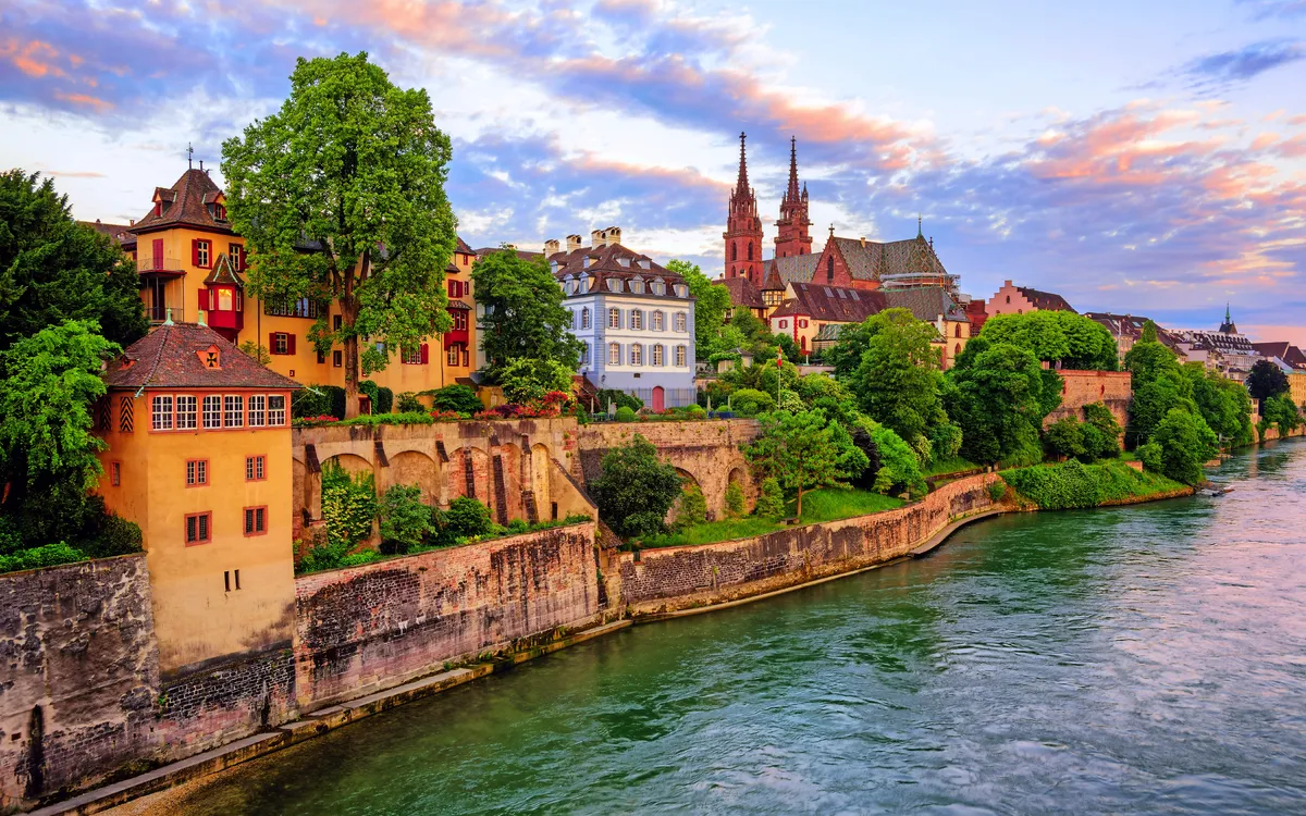 Historische Häuser und Kirche am Rhein in Basel bei Sonnenuntergang