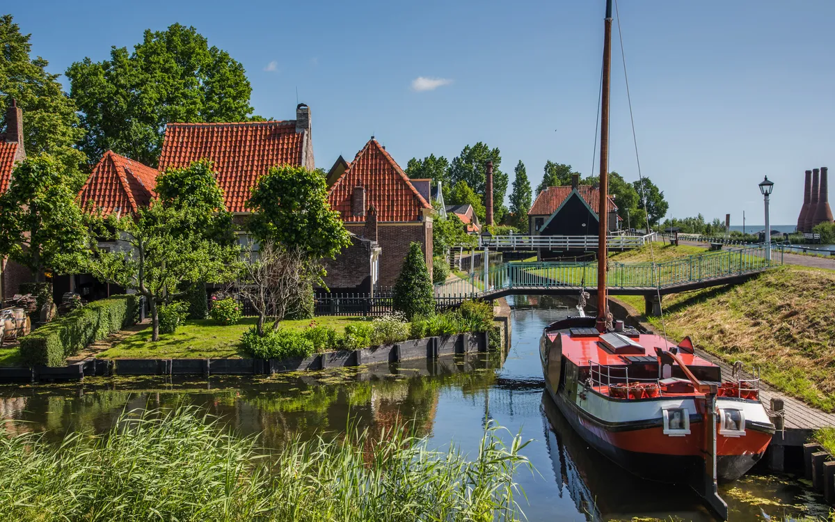 Alte Fischerhütten im Zuiderzeemuseum Enkhuizen am Kanal mit Segelboot.