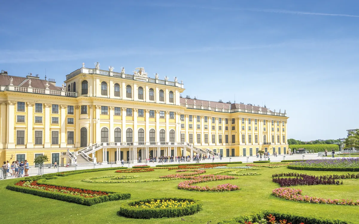 Schloss Schönbrunn in Wien bei Tageslicht mit blauem Himmel und Schlosspark.