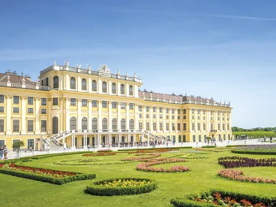 Schloss Schönbrunn in Wien bei Tageslicht mit blauem Himmel und Schlosspark.