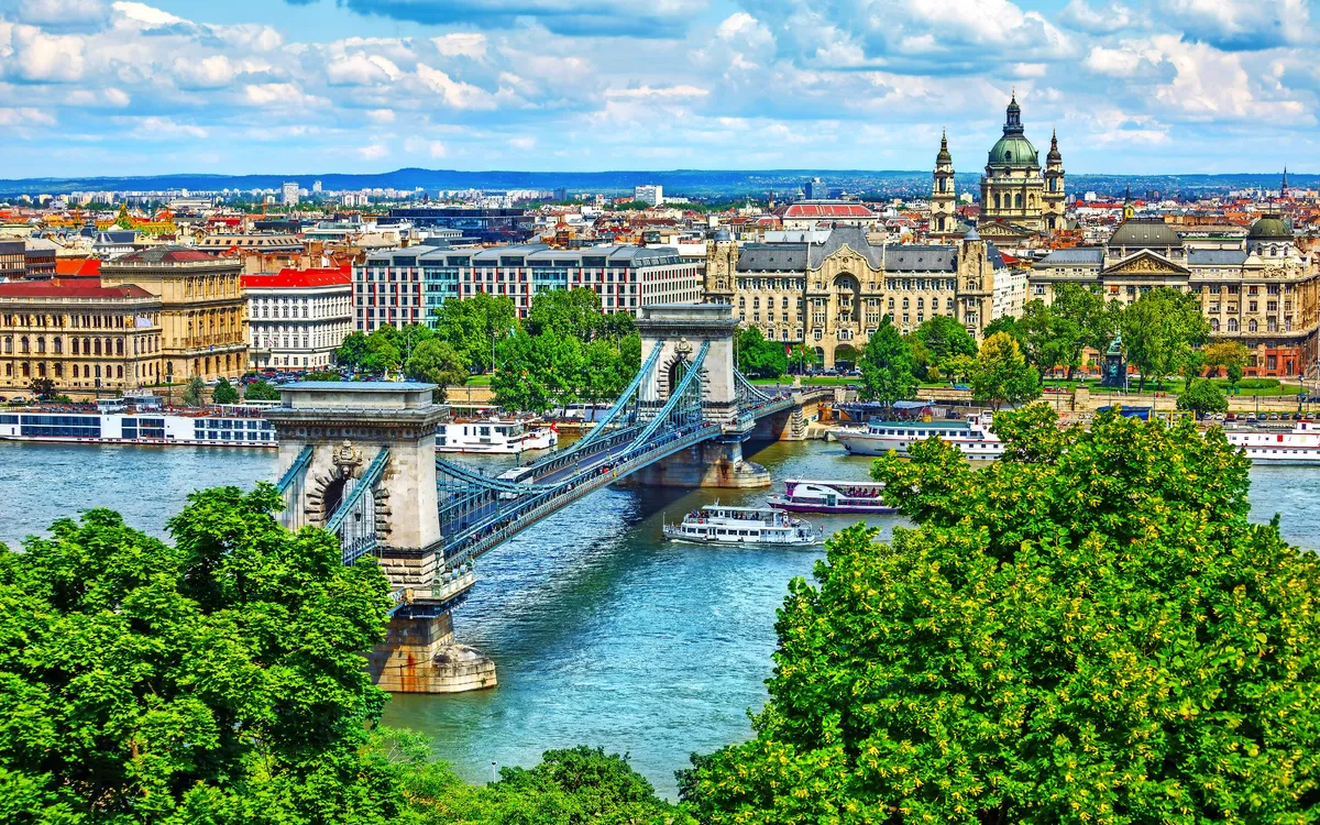 Kettenbrücke über die Donau in Budapest mit St.-Stephans-Basilika und Skyline im Hintergrund.