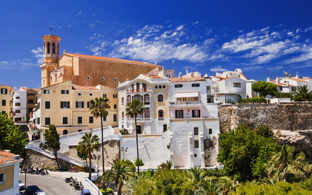 Pastellfarbene Gebäude in Mahón auf der Insel Menorca, unter klarem blauem Himmel.