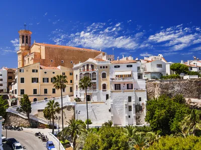 Pastellfarbene Gebäude in Mahón auf der Insel Menorca, unter klarem blauem Himmel.