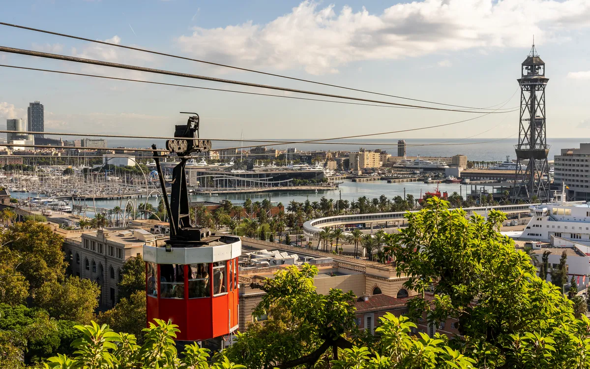 Rote Seilbahnkabine über Barcelona mit Blick auf Hafen und Stadtpanorama